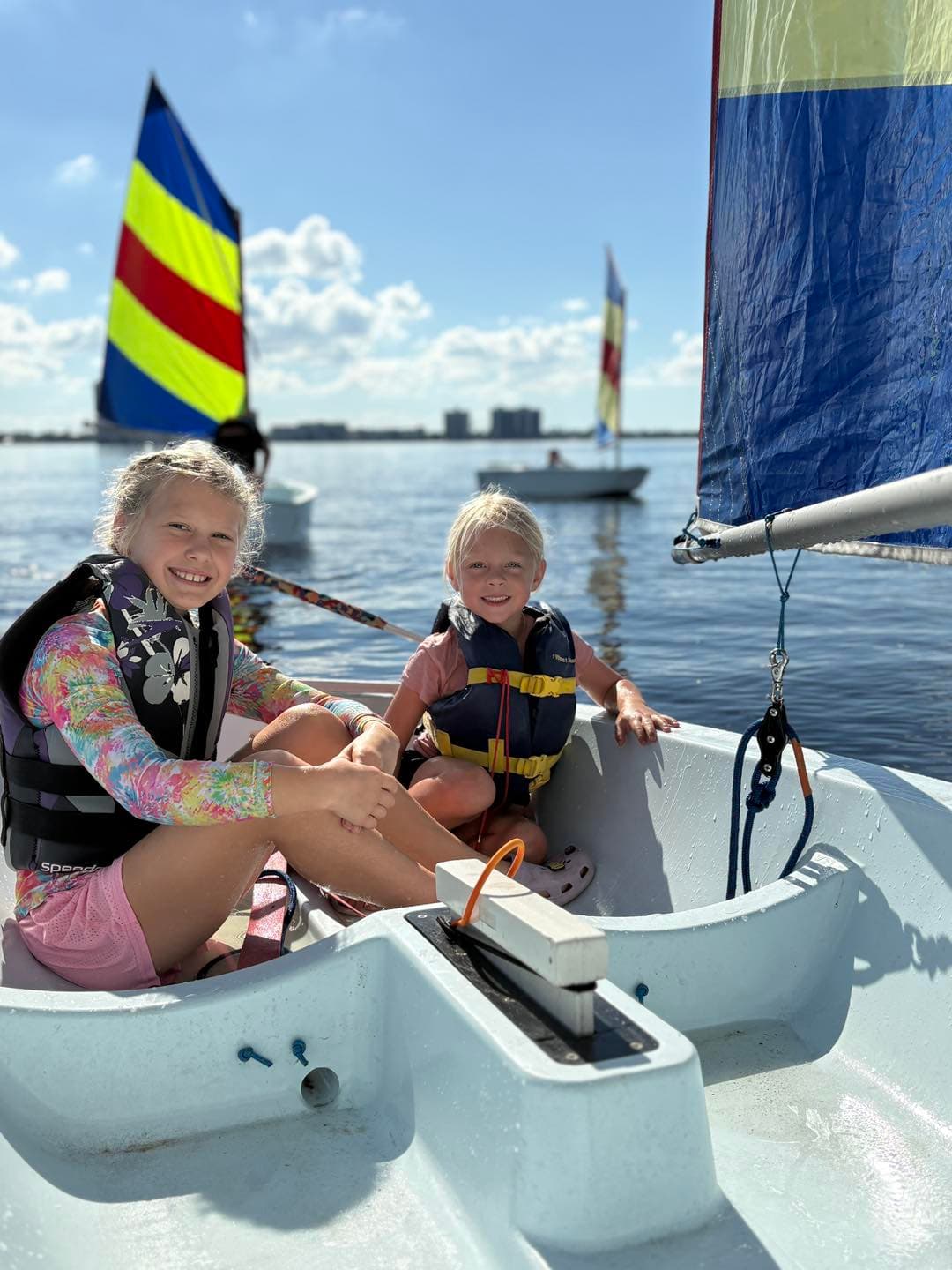 Two young girls smiling aboard a sailboat