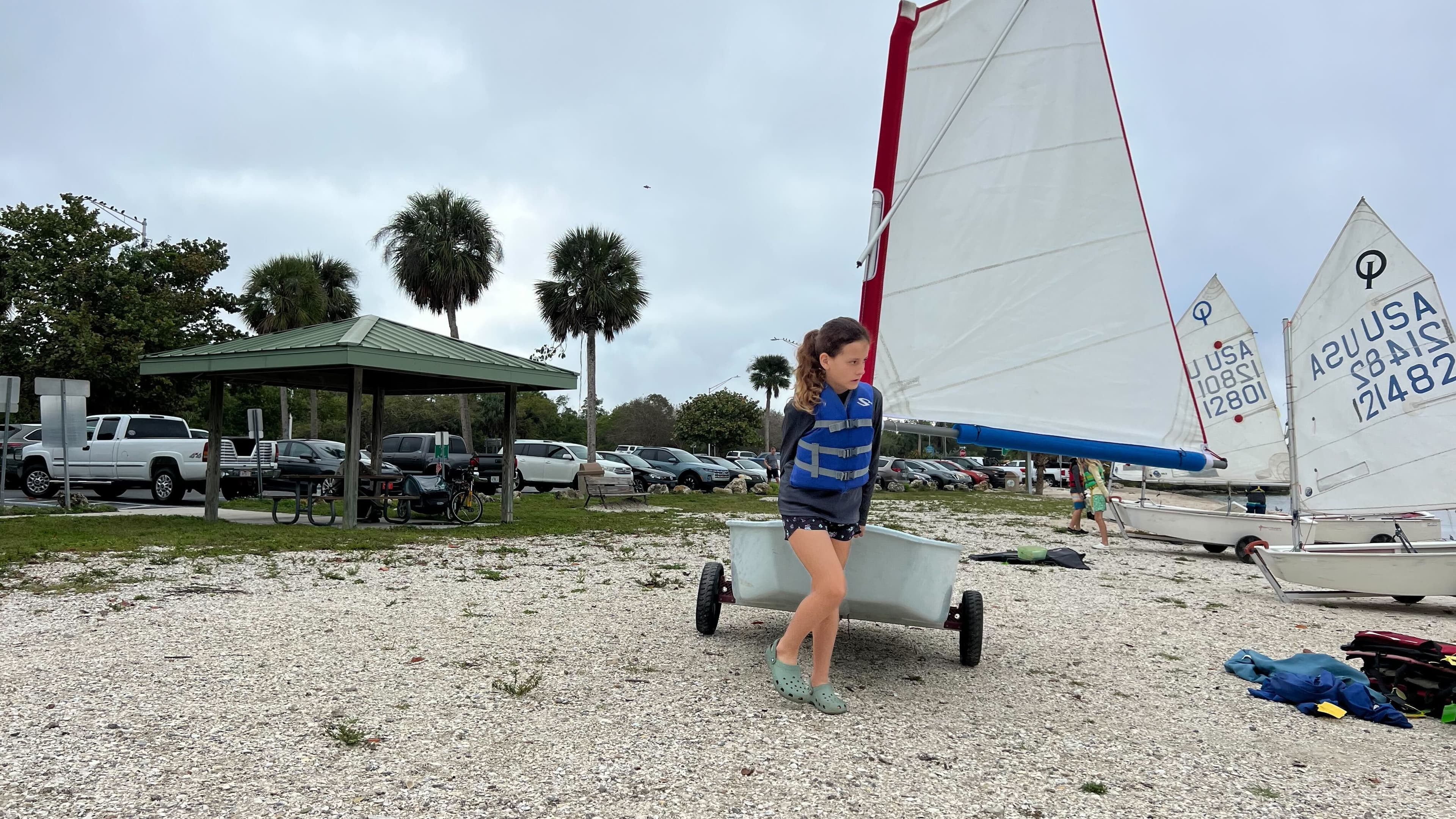 Young girl sitting in an Optimist sailboat