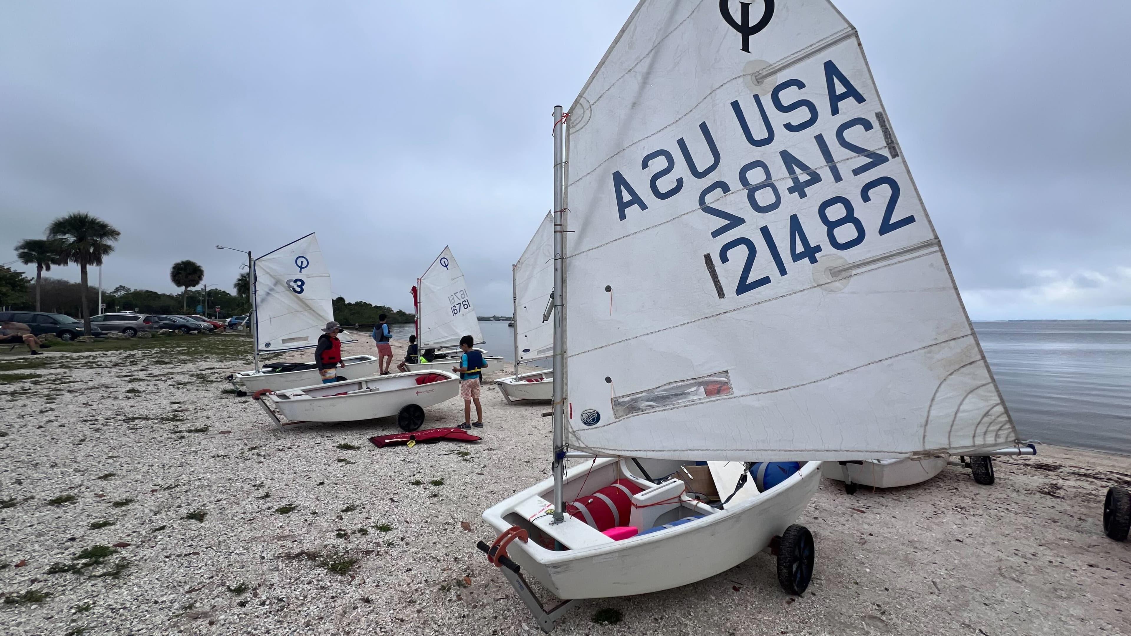 Optimist fleet with sails raised on the beach